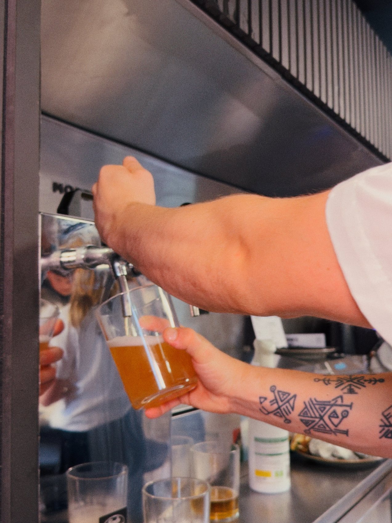 A barista pouring a coffee at Ruger Fjord, with the espresso machine in the background.