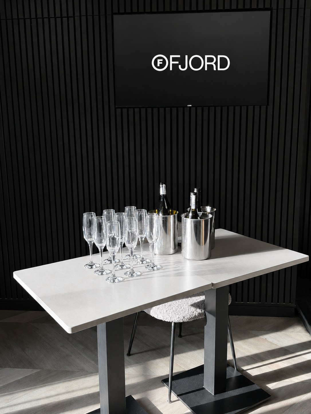 A laid table with wine glasses and bottles against the Ruger Fjord black slatted interior wall.