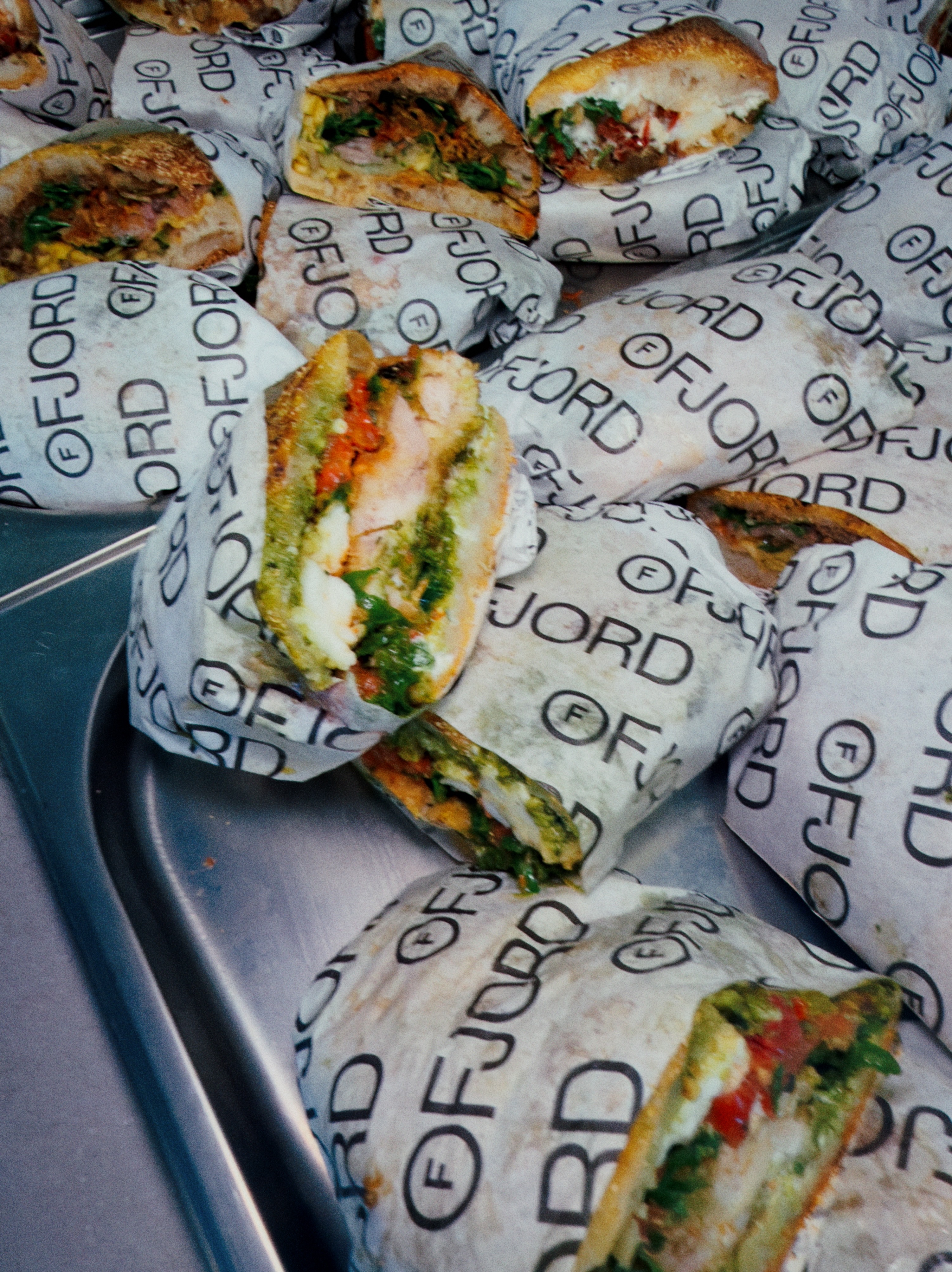 Freshly wrapped Ruger Fjord focaccia sandwiches in branded paper, packed on a tray.