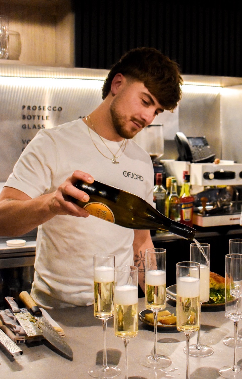 A member of the Ruger Fjord team pouring prosecco into glasses at the bar.